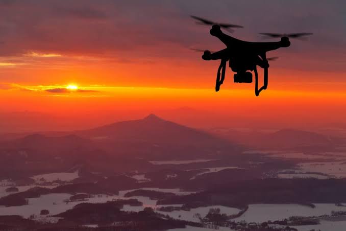 Drone flying over rural land at sunset